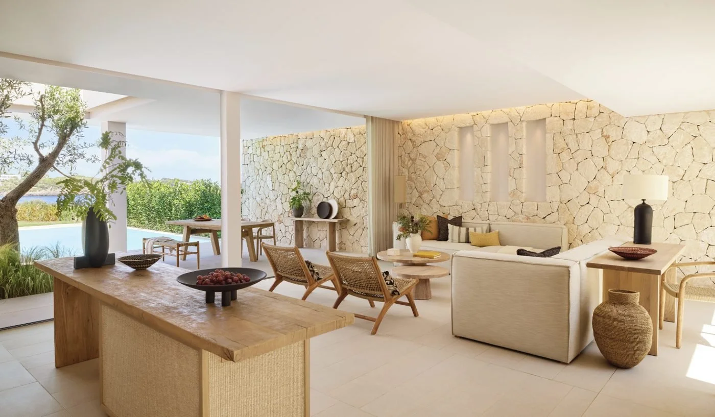 The open-plan living space of a Deluxe Two Bedroom Residence, with stone walls and doors open to a private pool