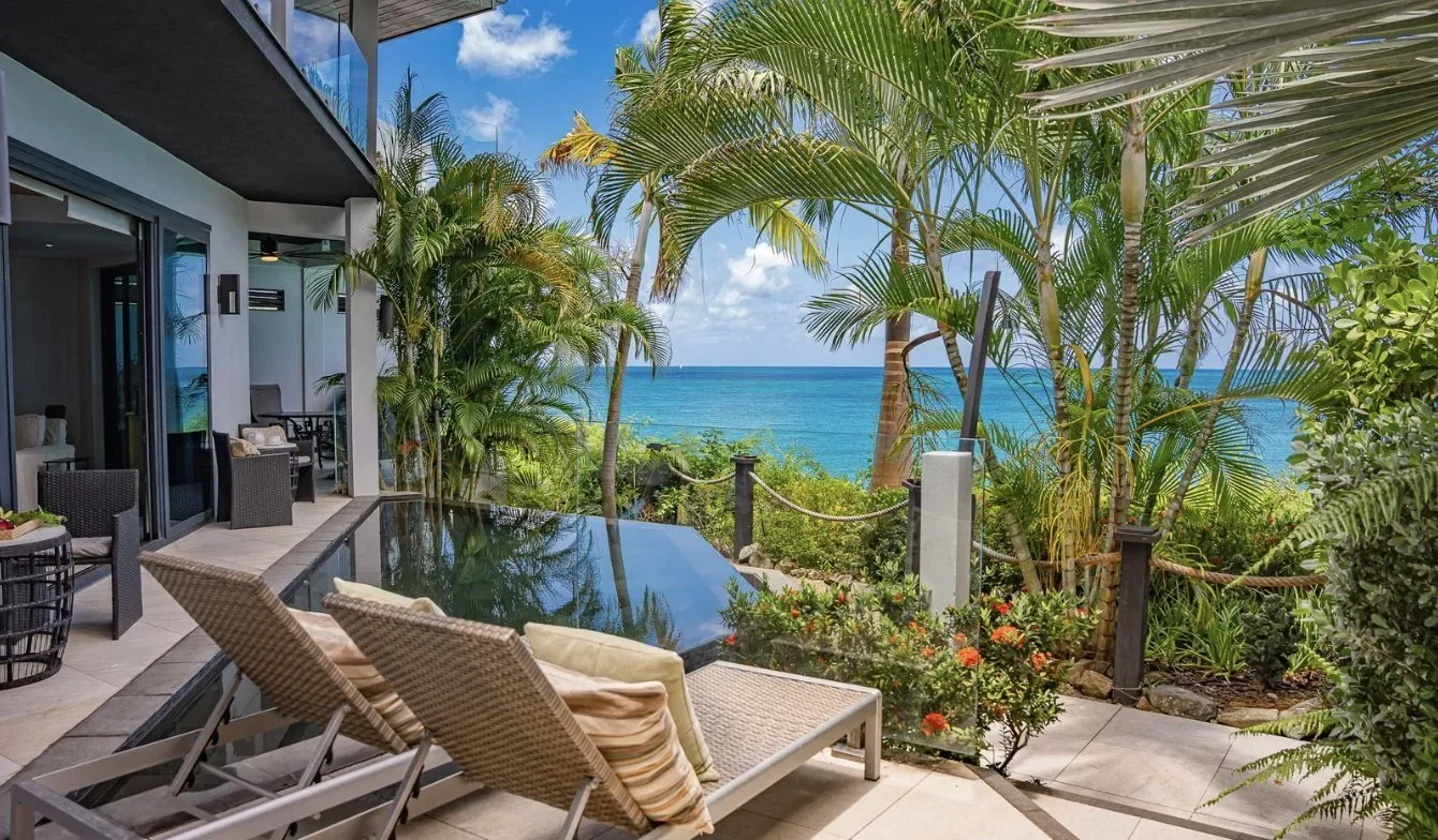 A villa terrace with loungers among palms and sea views