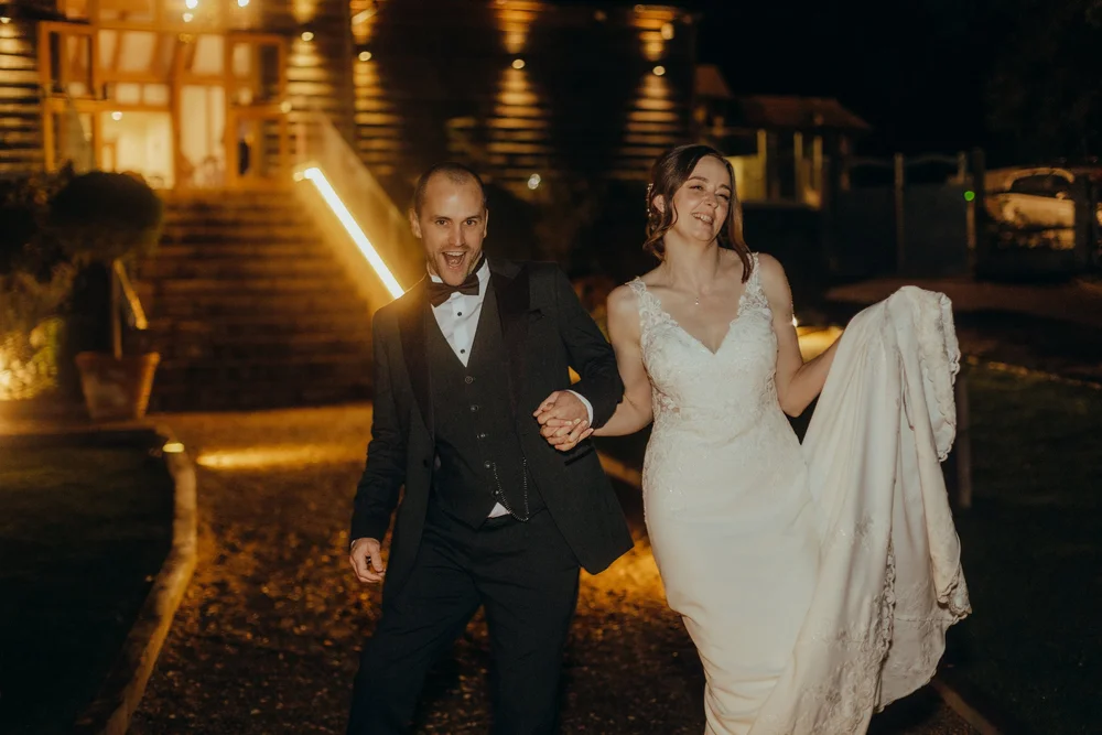 Couple leaving the venue at night, bride holding her dress