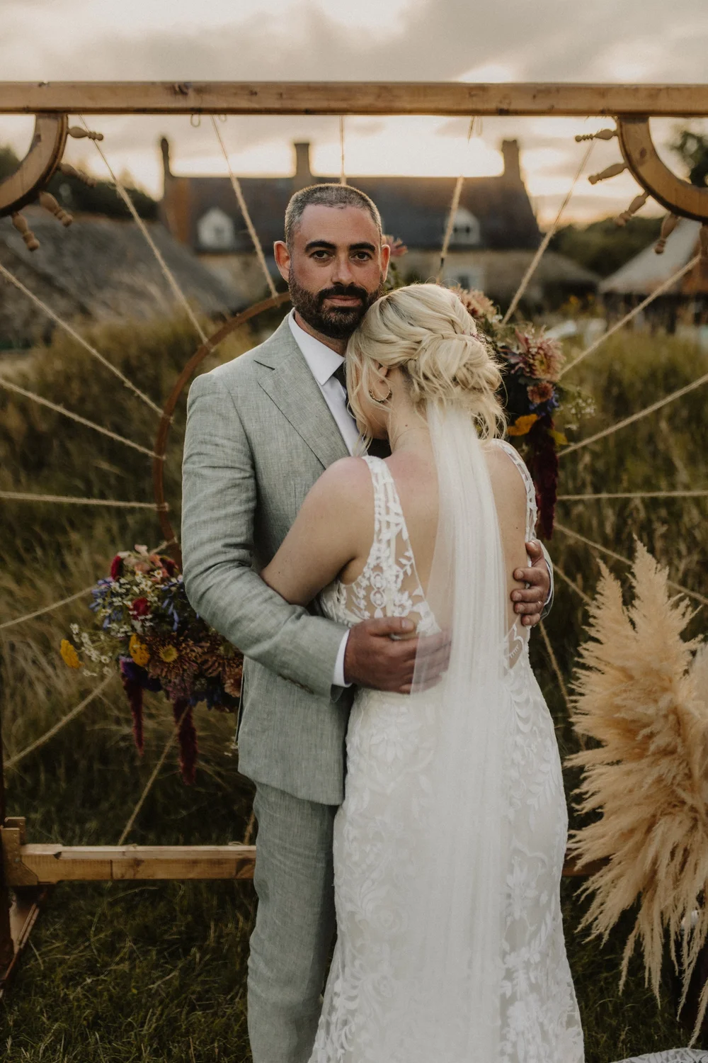 Bride and groom hugging in front of a pampas grass backdrop