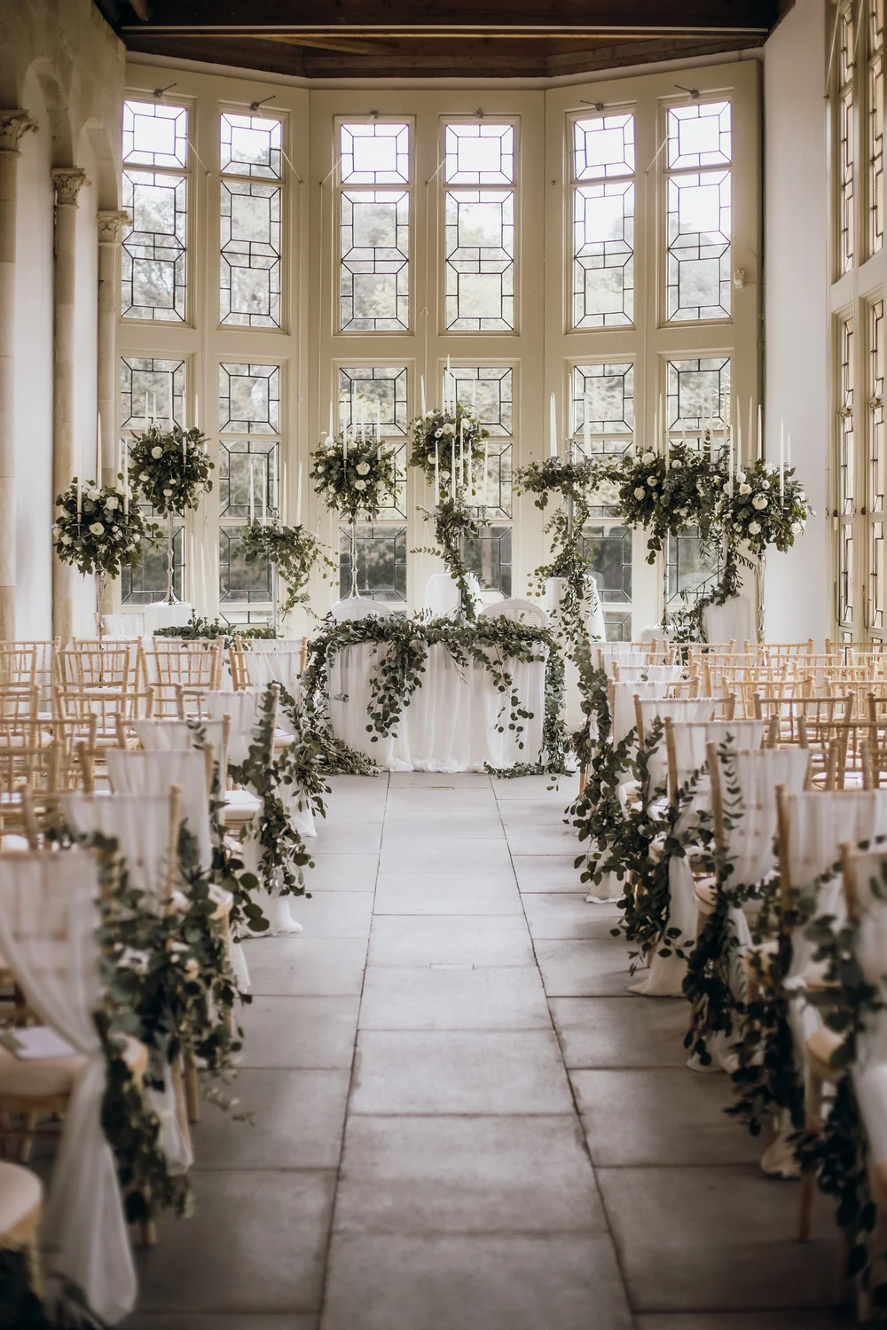 Orangery set for a ceremony with greenery down the aisle