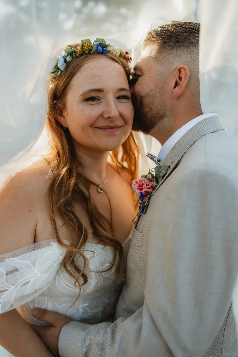 Groom kissing the smiling bride on the cheek