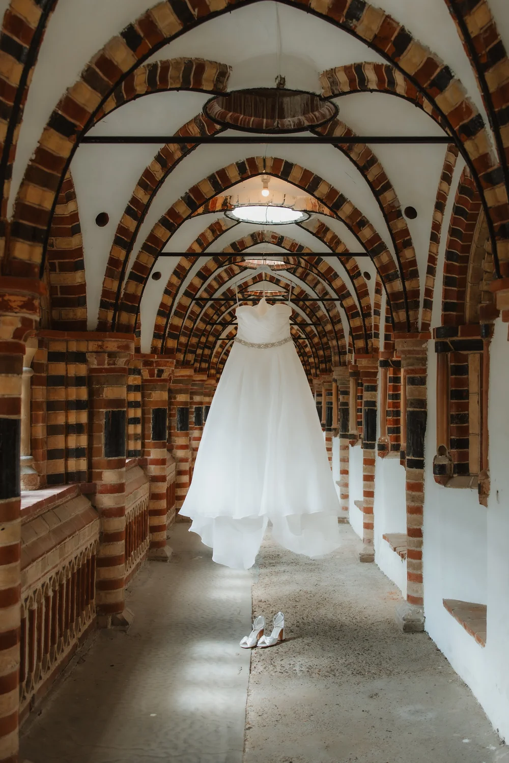 Wedding dress hanging in an arched corridor