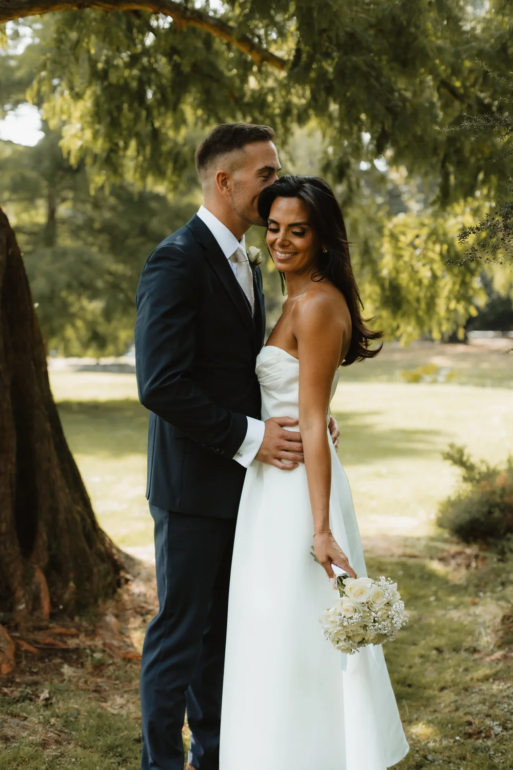 Bride and groom beneath a tree in the grounds