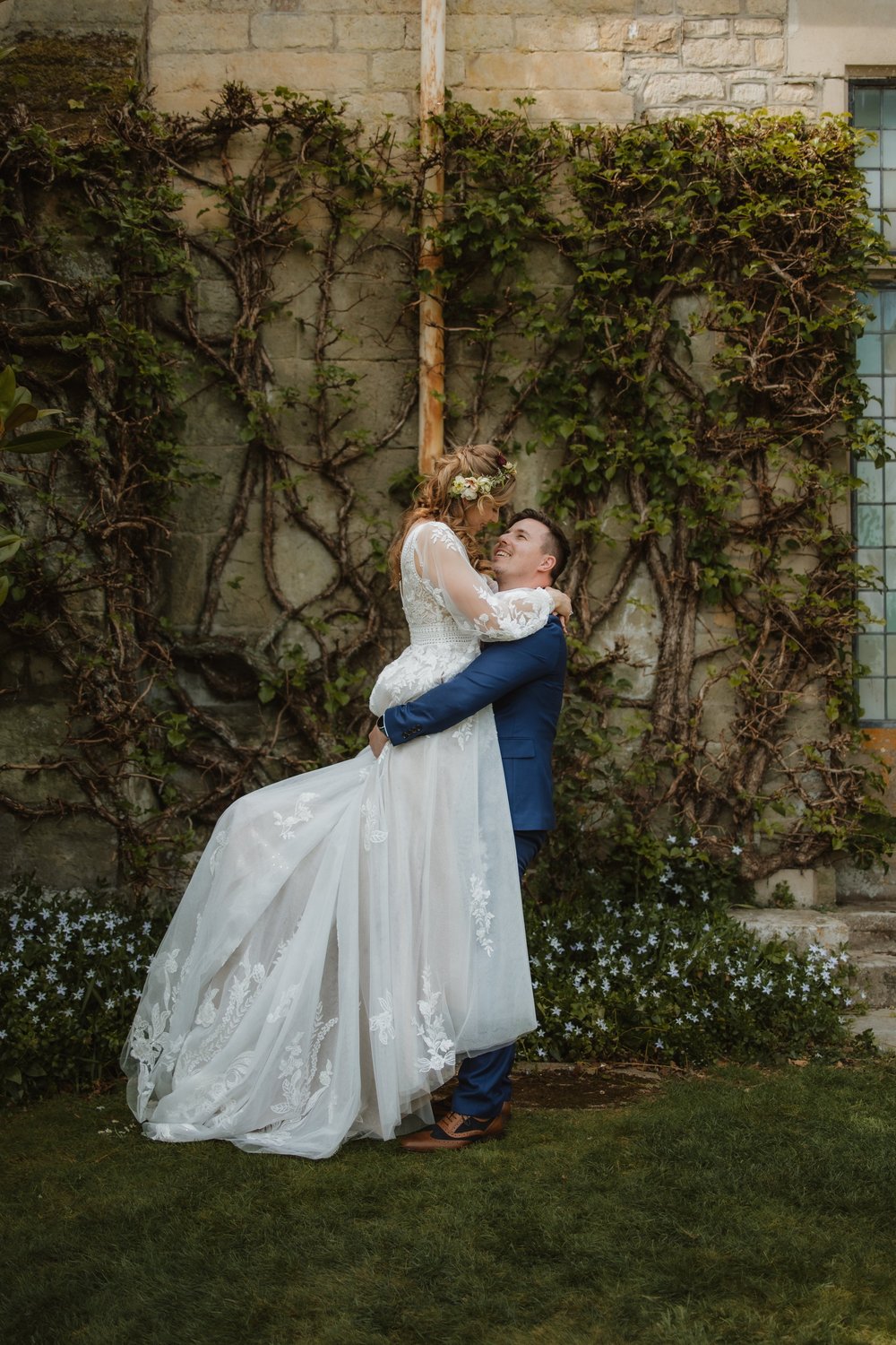 Groom lifting the bride beneath wisteria