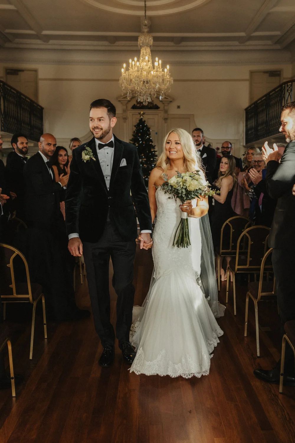 Newlyweds walking back up the aisle under a chandelier