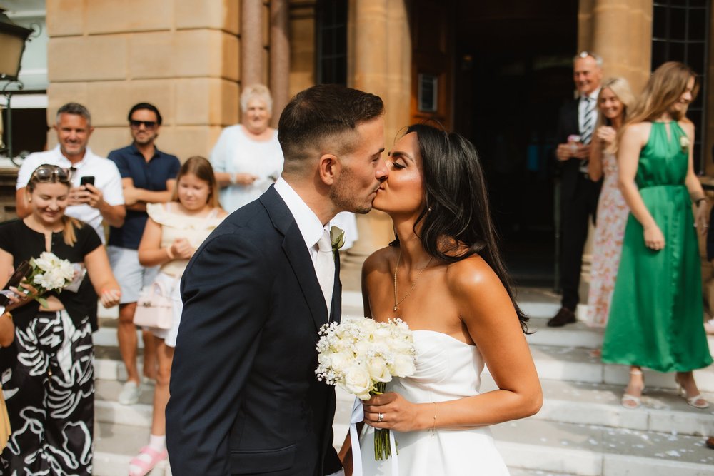 Couple kissing after the ceremony as guests watch