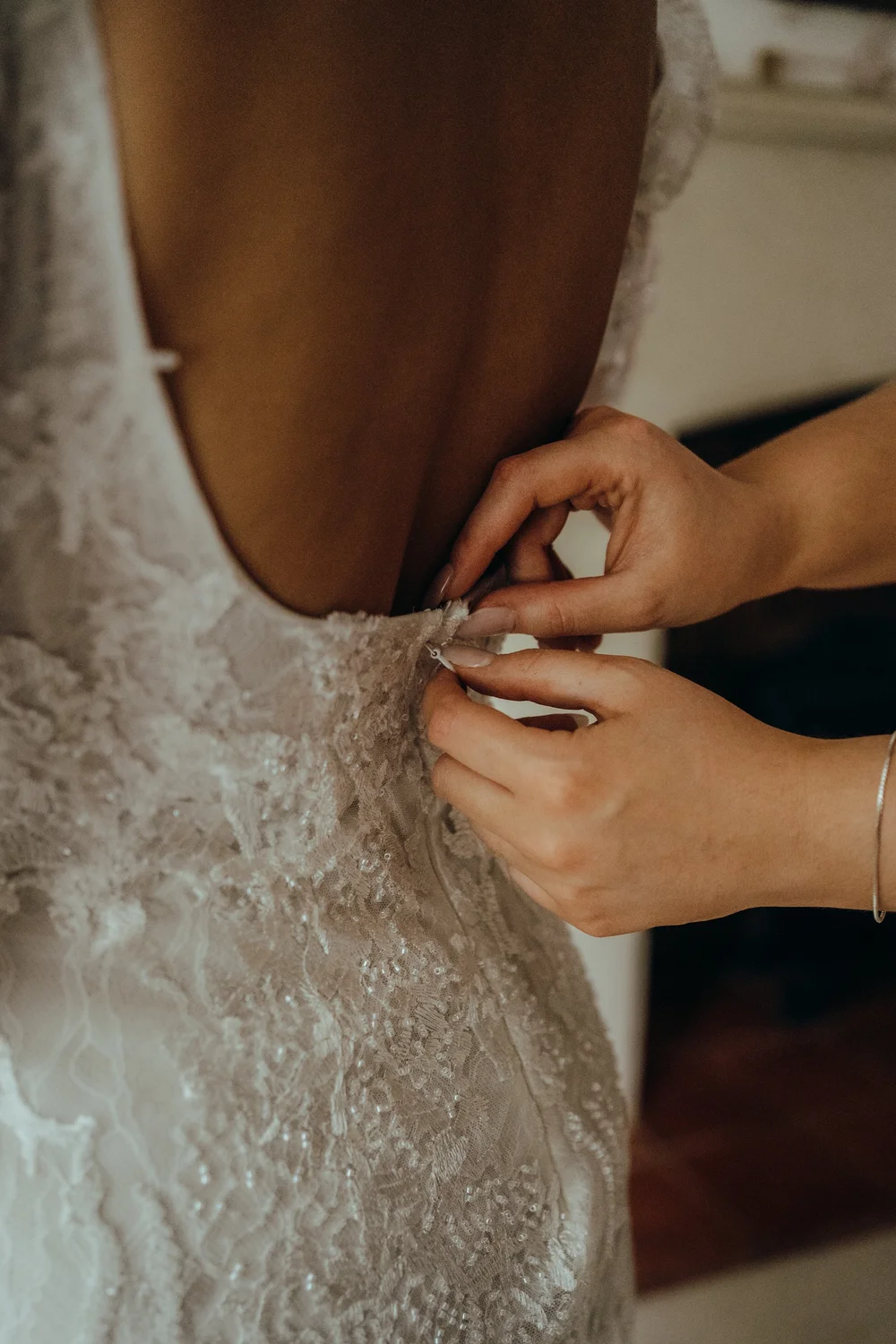 Bridesmaid fastening the back of the wedding dress