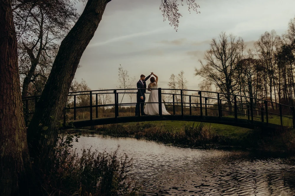 Couple on a wooden bridge over a lake at dusk
