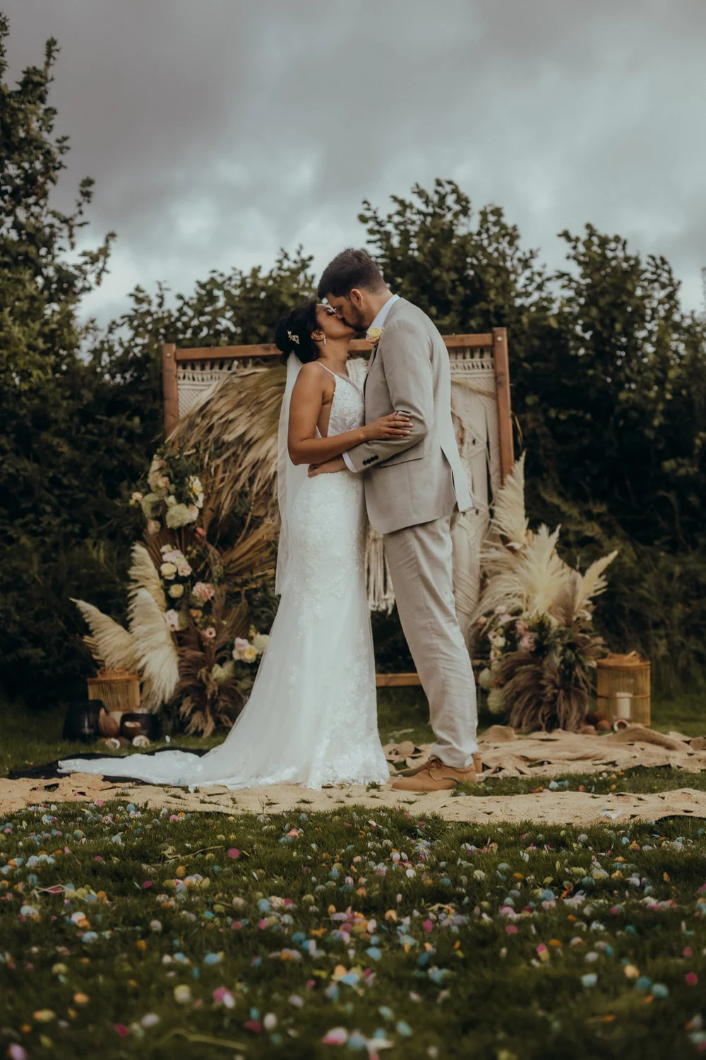 Couple kissing in front of a pampas arch
