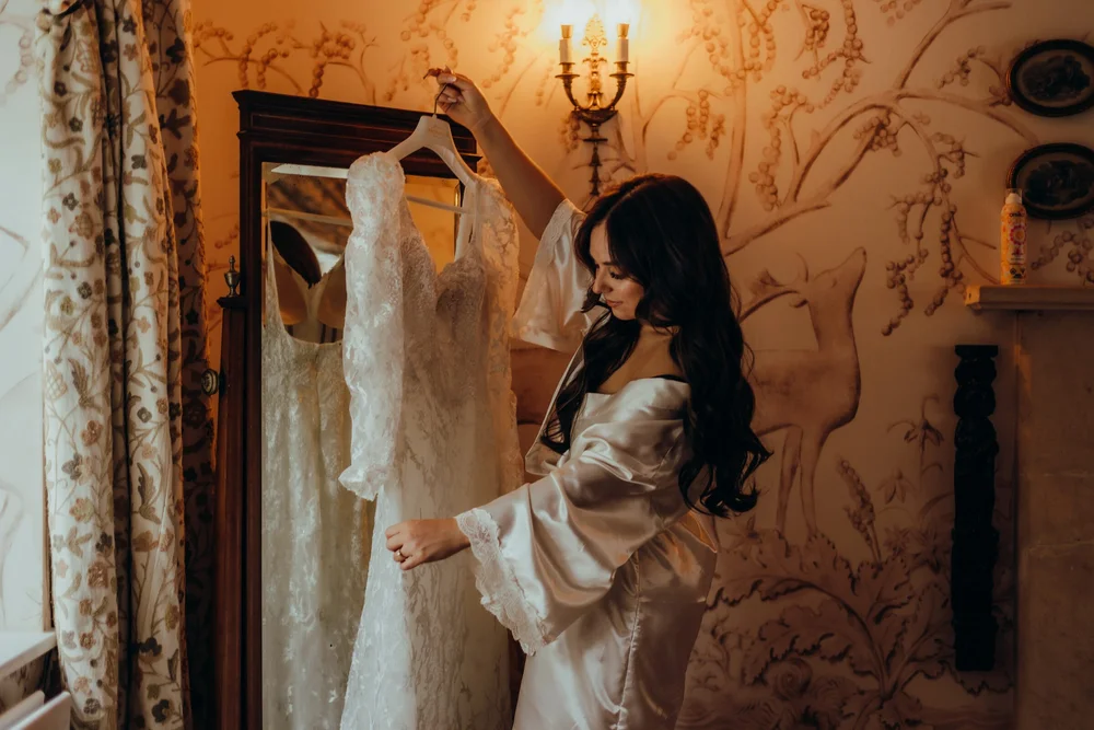 Bride in her robe reaching for her wedding dress