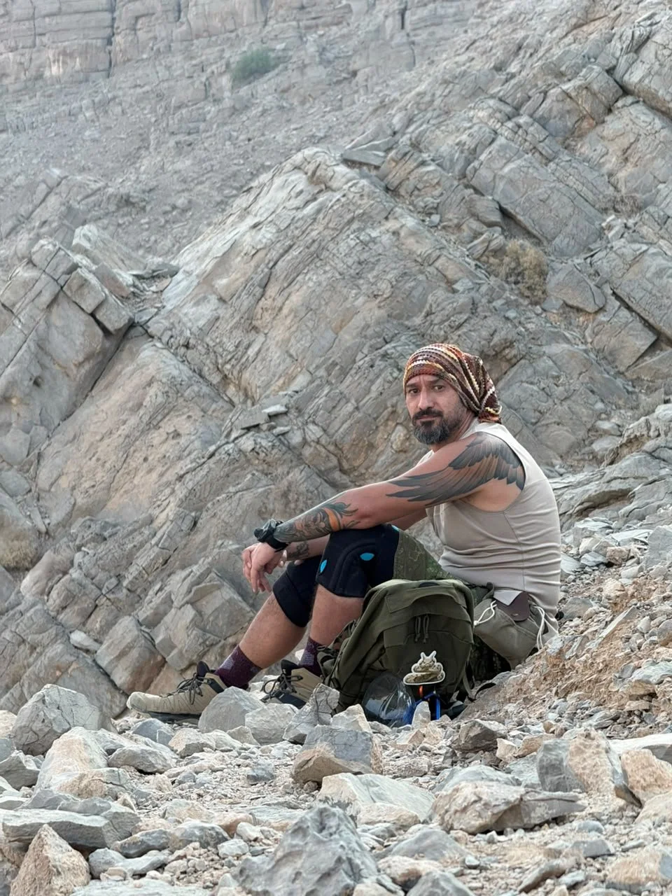Wildlife photographer resting on a rocky mountain slope in the UAE