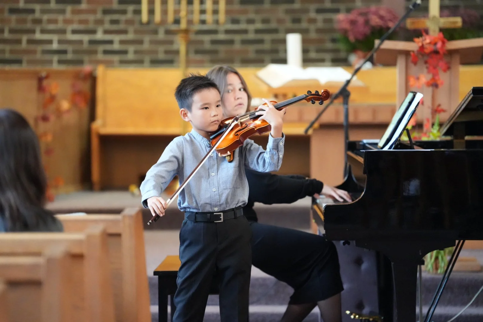 Student playing violin with piano in the background