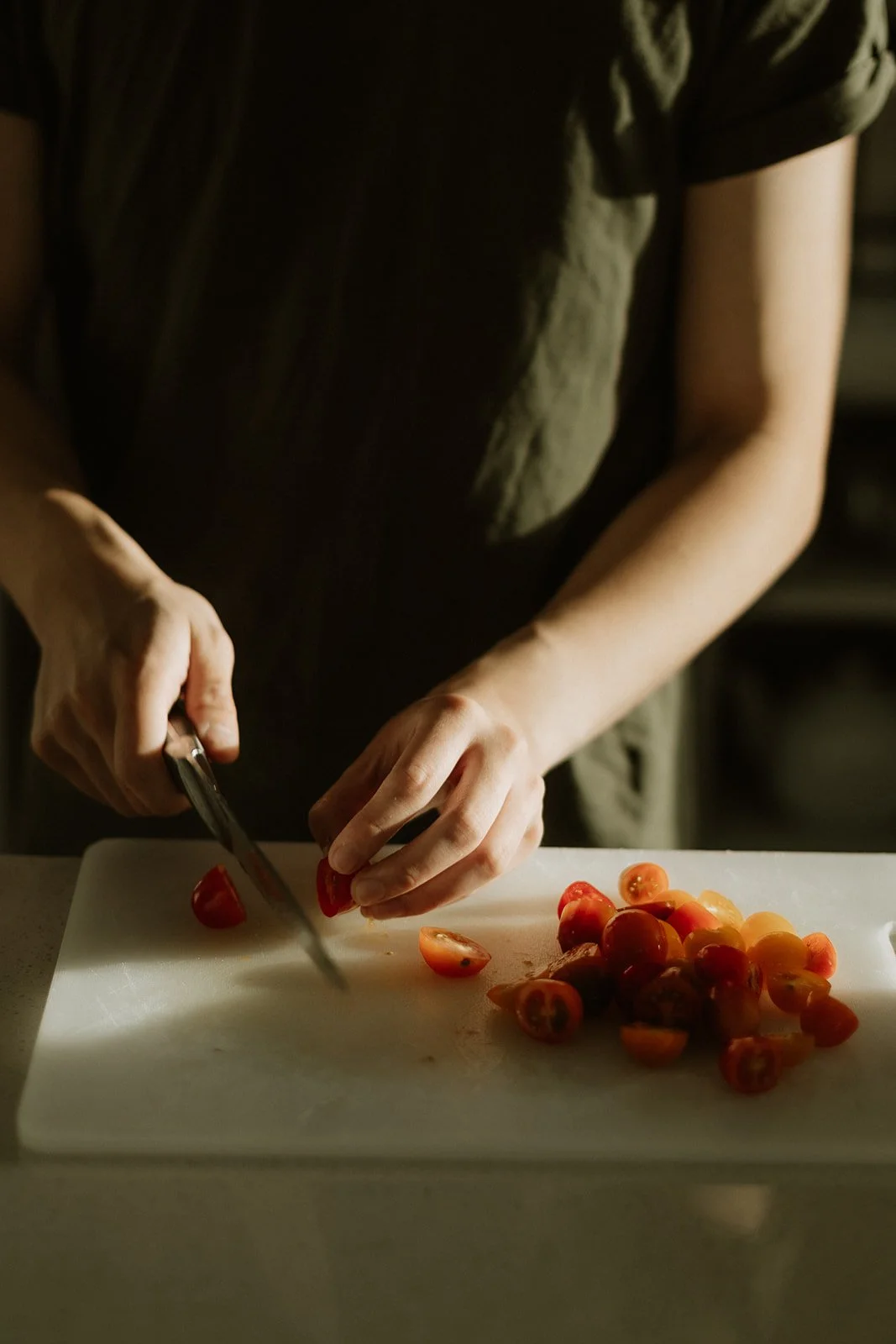 Close view of hands slicing red peppers on a wooden board