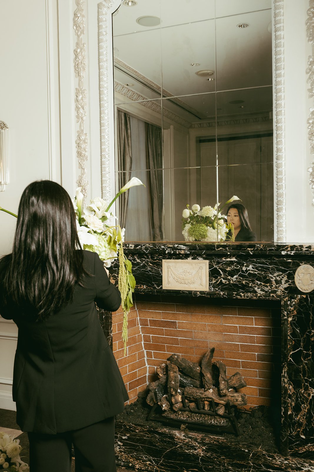 A florist arranging white calla lilies on a black marble mantel