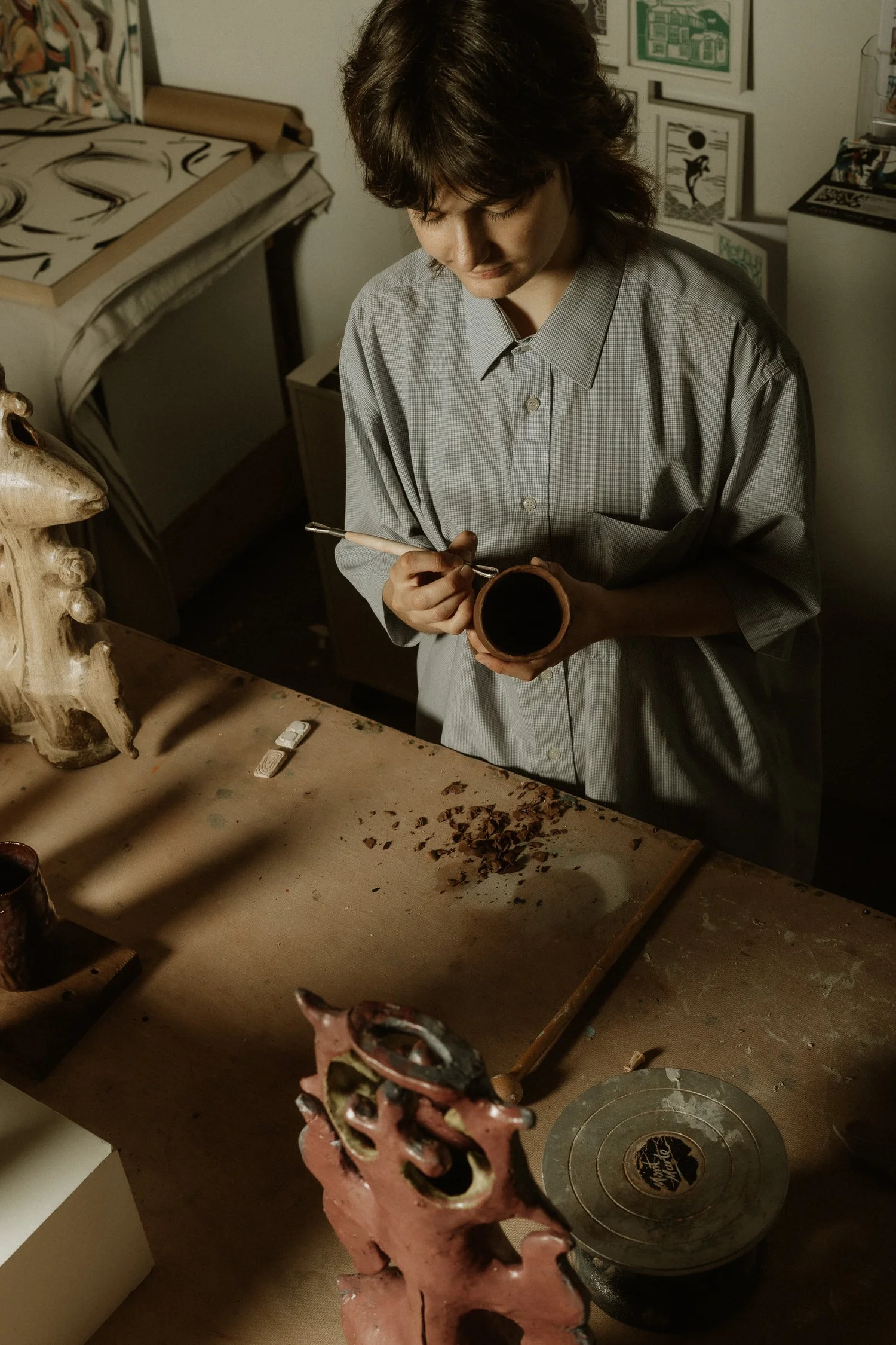 A ceramicist carving detail into a small clay piece at her bench