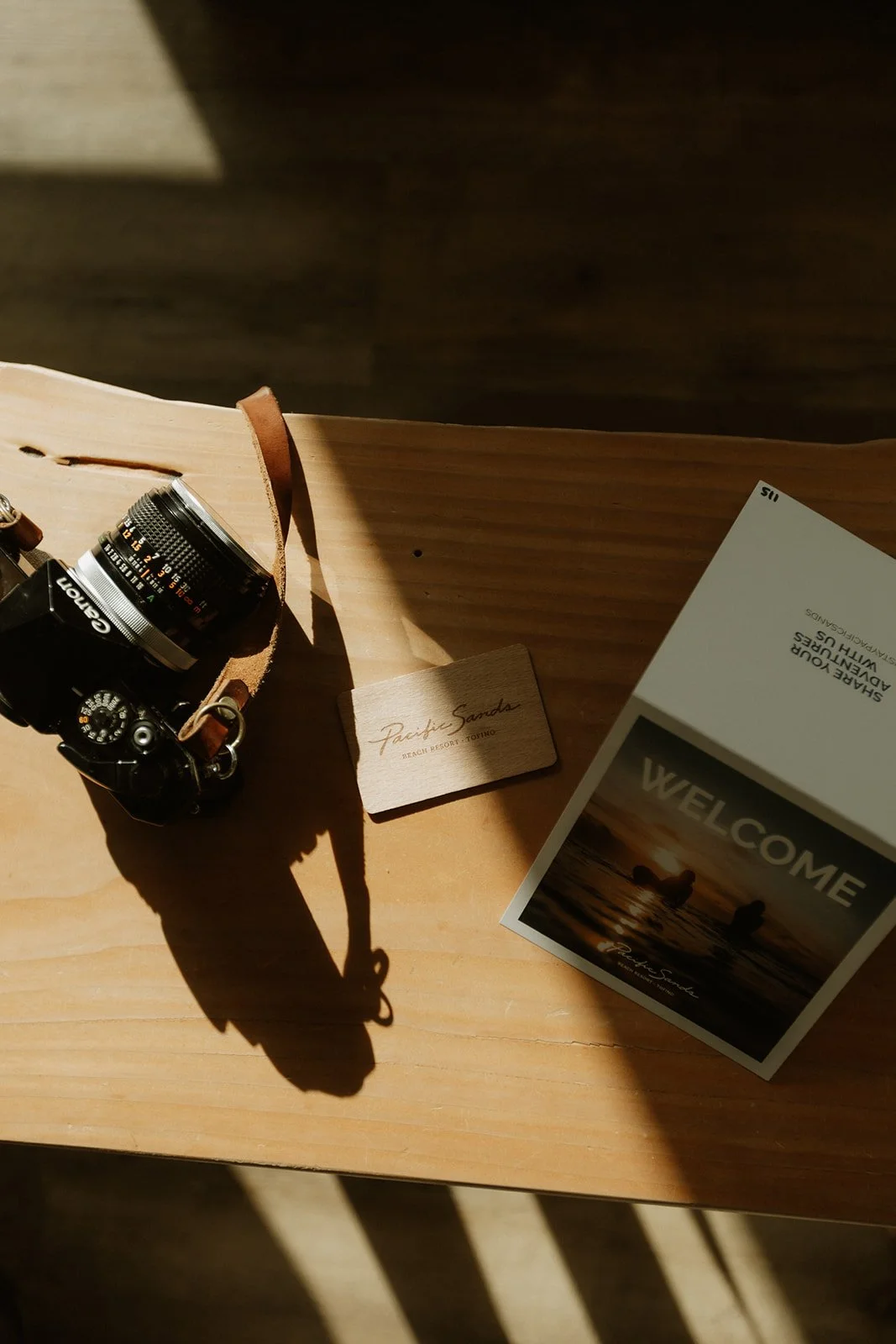 A film camera and printed cards on a sunlit wooden table