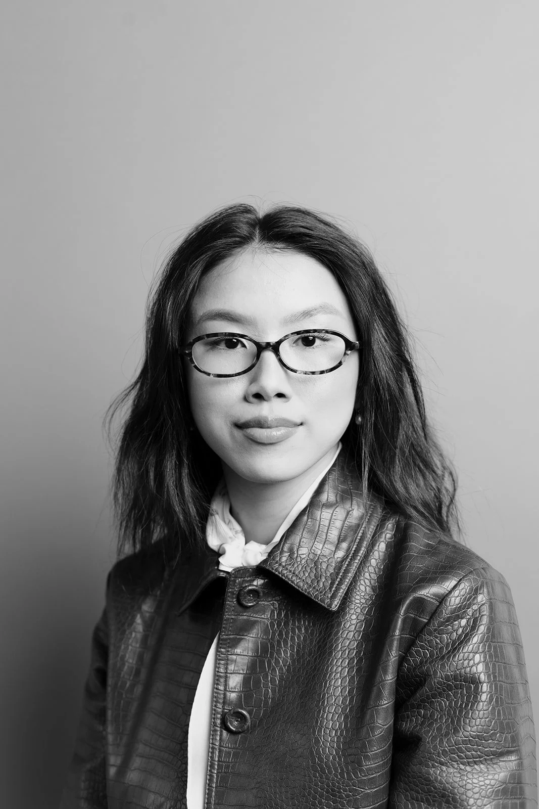 Black and white portrait of a woman in glasses and a leather jacket