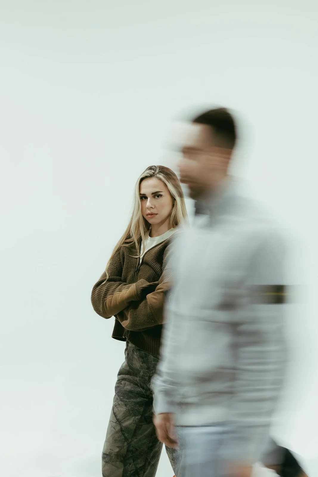 A woman standing still as a man walks past in a motion blur