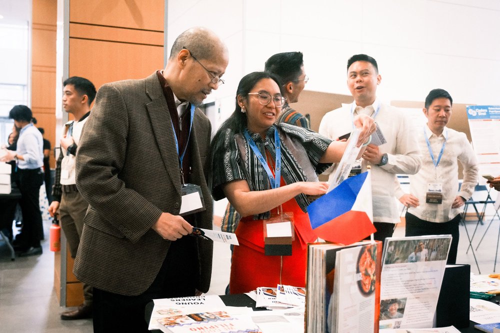Attendees and physicians browsing a resource table with a Philippine flag