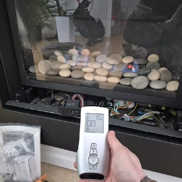 Technician testing a gas fireplace remote after a repair