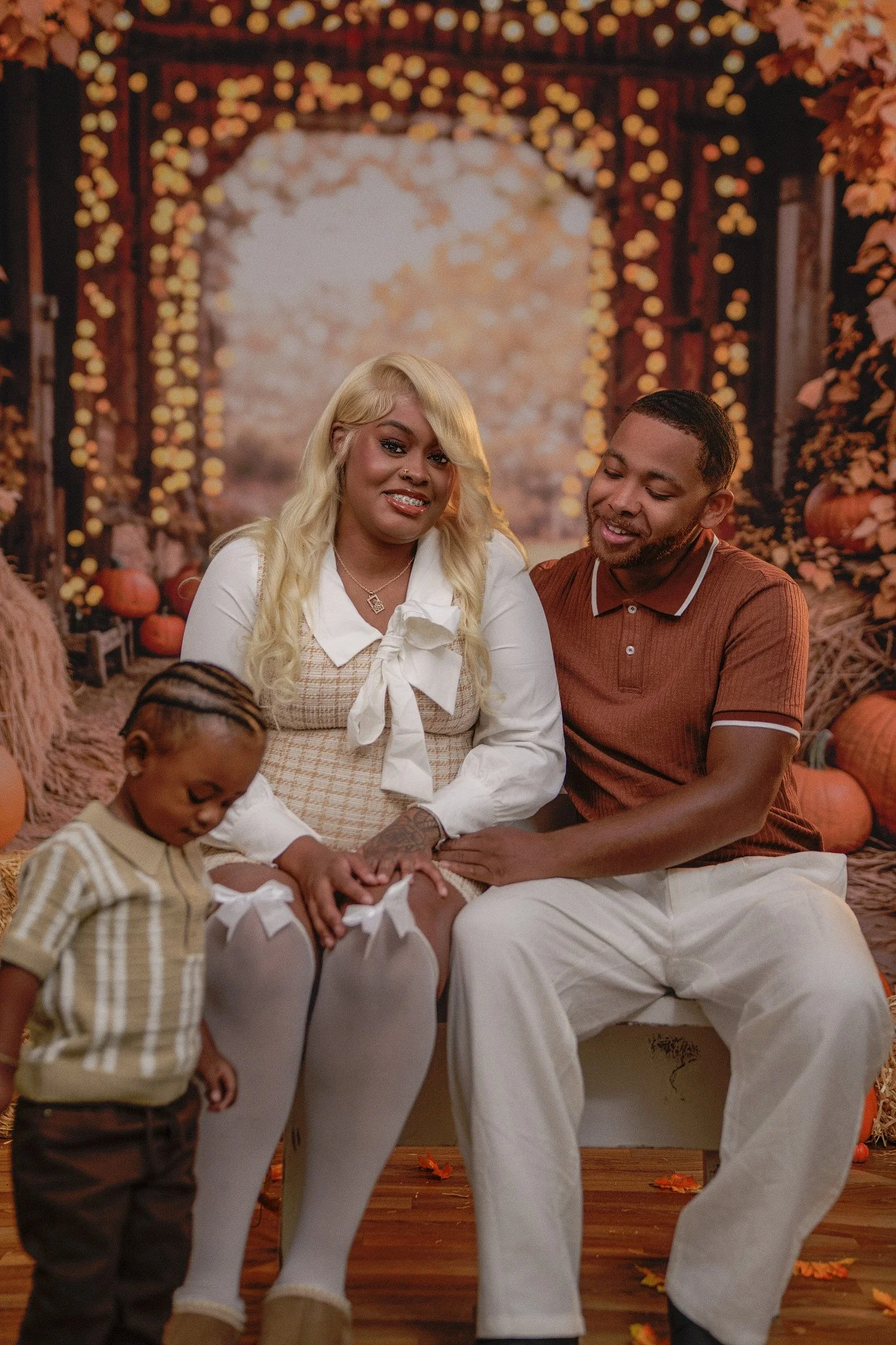 Family of three seated at fall backdrop