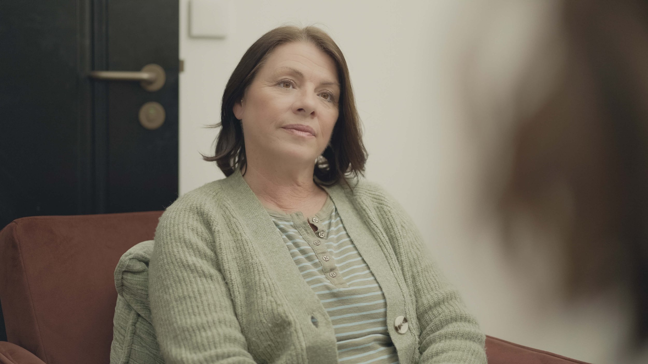 A therapist listening to another person during a seated conversation.