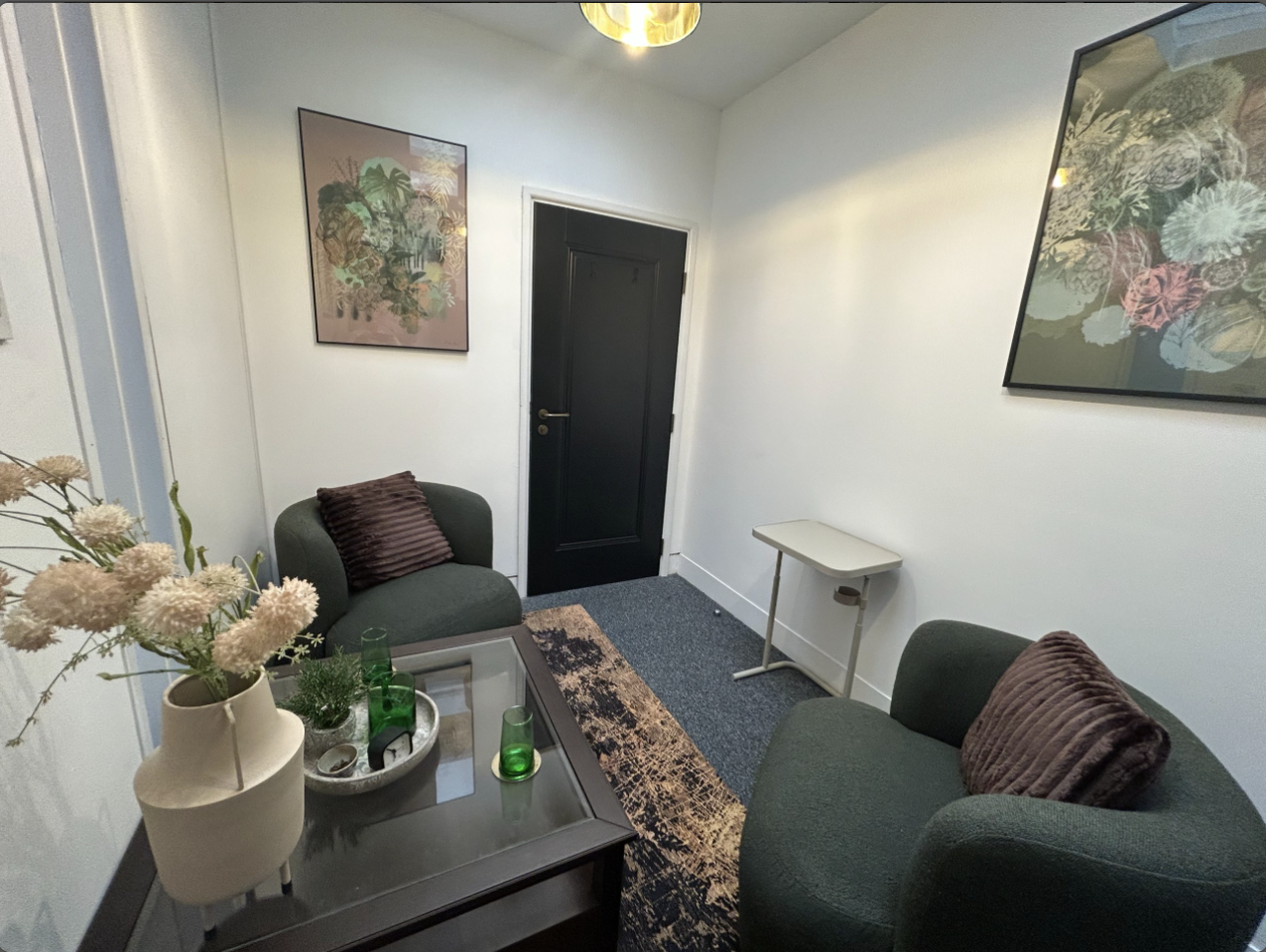 Affiniti+ Room 4 with two armchairs, side table, floral artwork and a small desk.