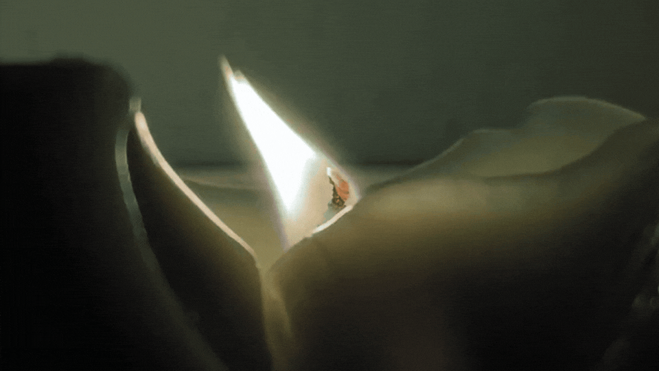 A single candle flame burning in the dark