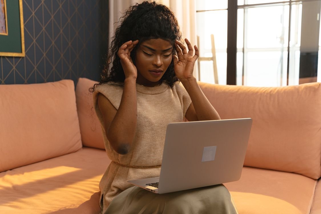 Woman touching her temples at a laptop