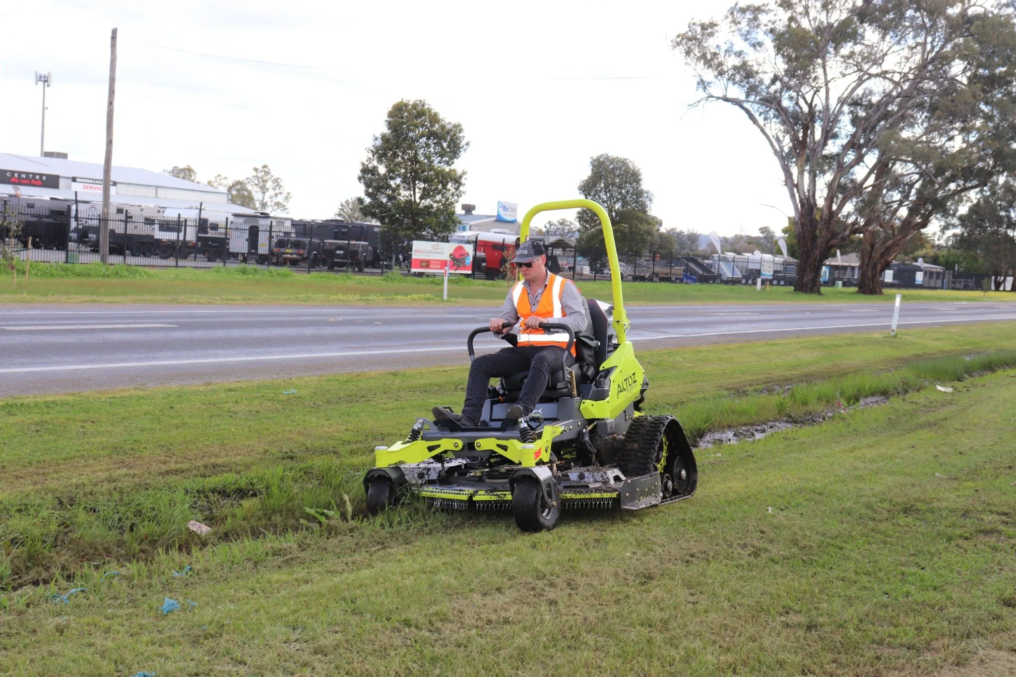 Operator using an Altoz TFX on uneven grass beside a drainage channel