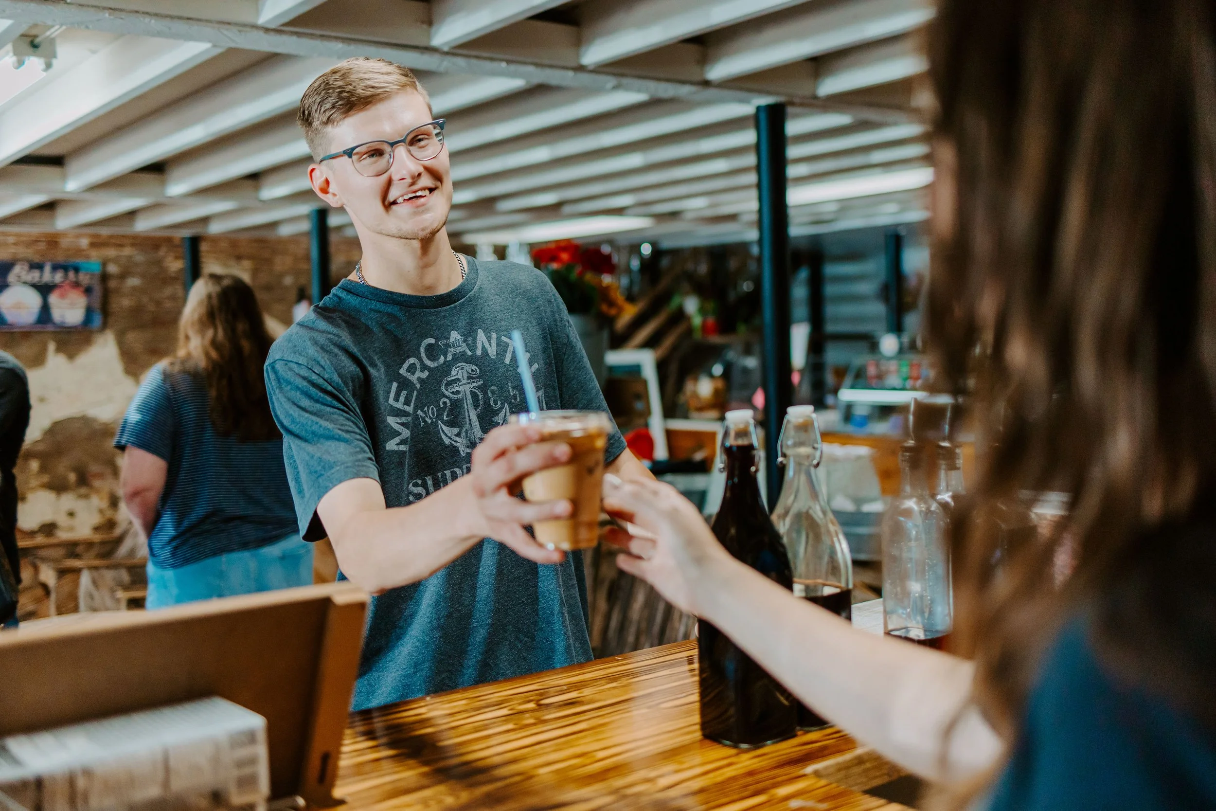 Barista handing a coffee drink to a guest at a Promise Coffee cart