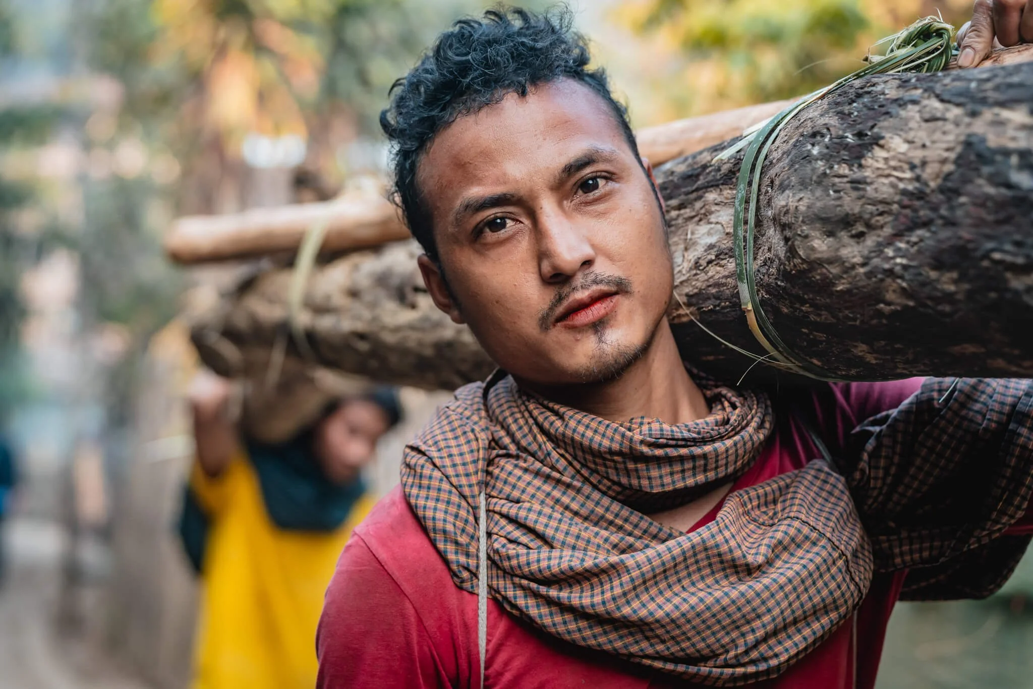 Karen man in Burmese refugee camp carries a log for house construction, The Border Consortium.