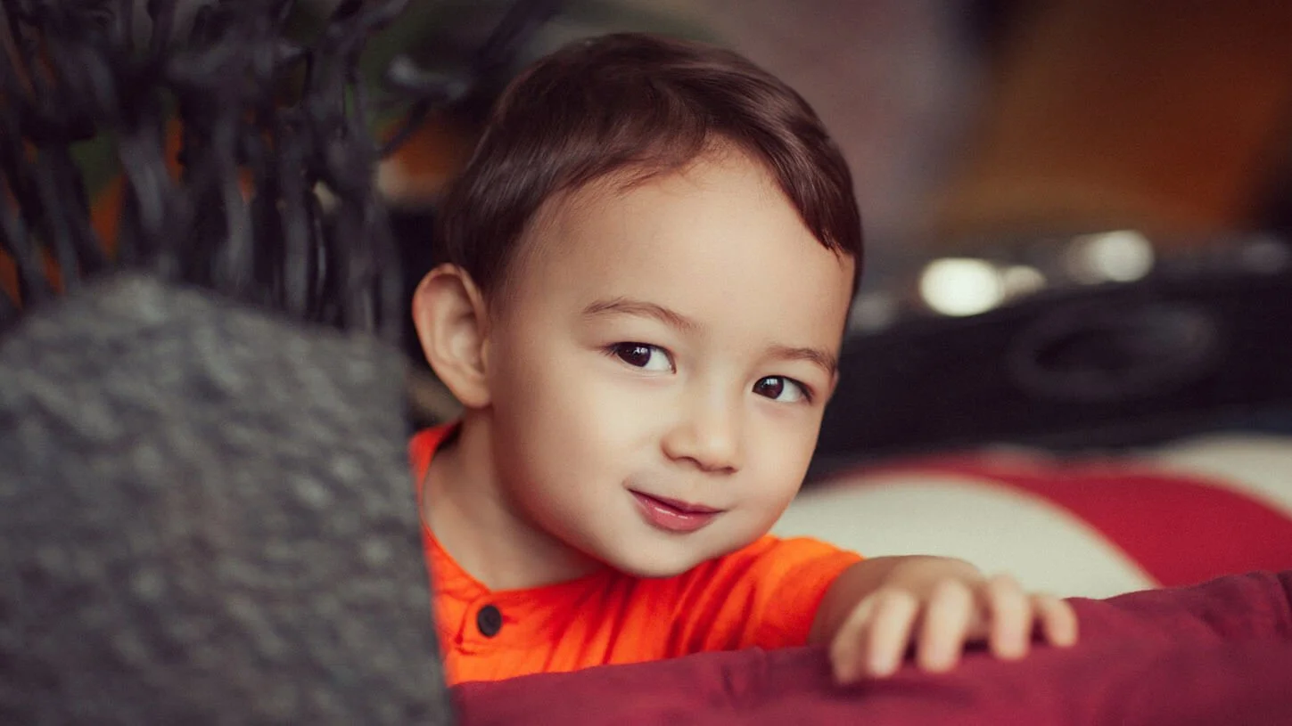 Portrait of a boy peaking around a plant, Hong Kong
