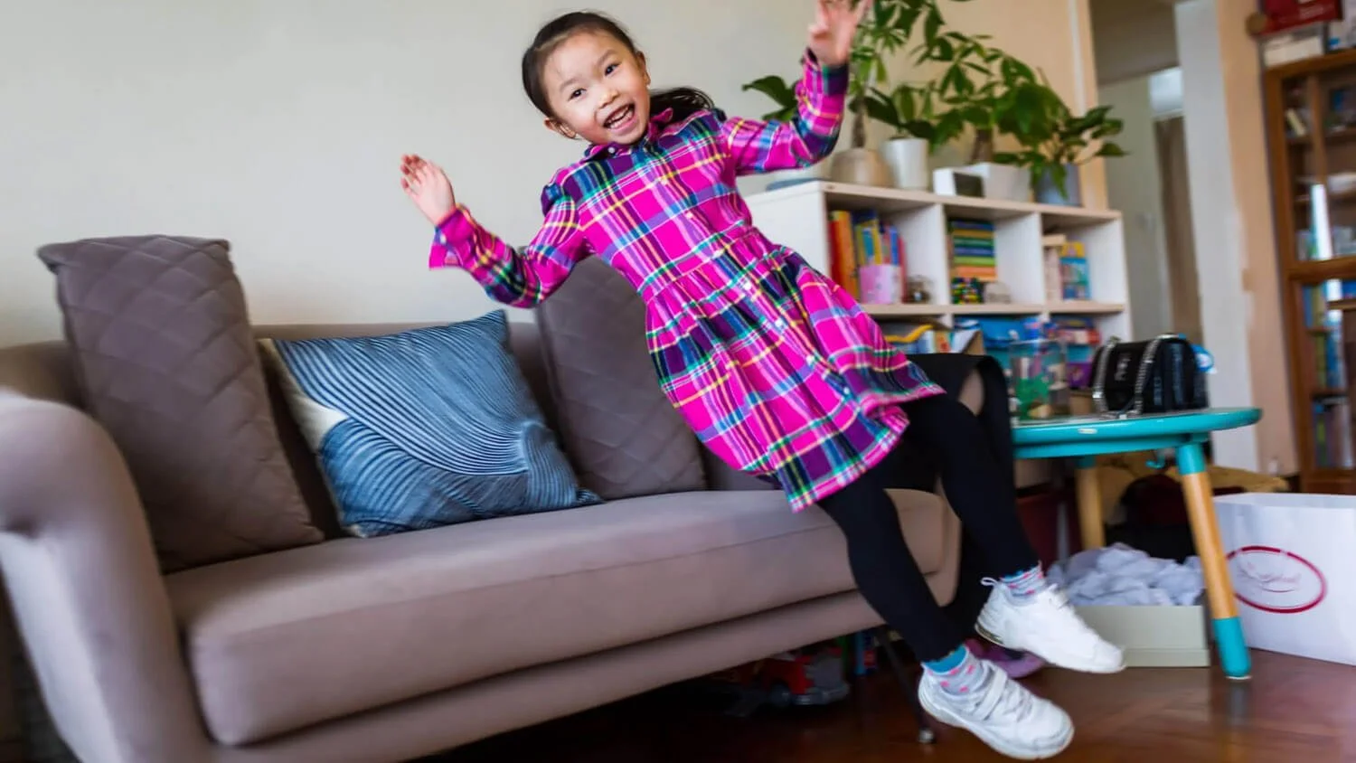 Girl laughs as she jumps on the sofa in Clear Water Bay Hong Kong