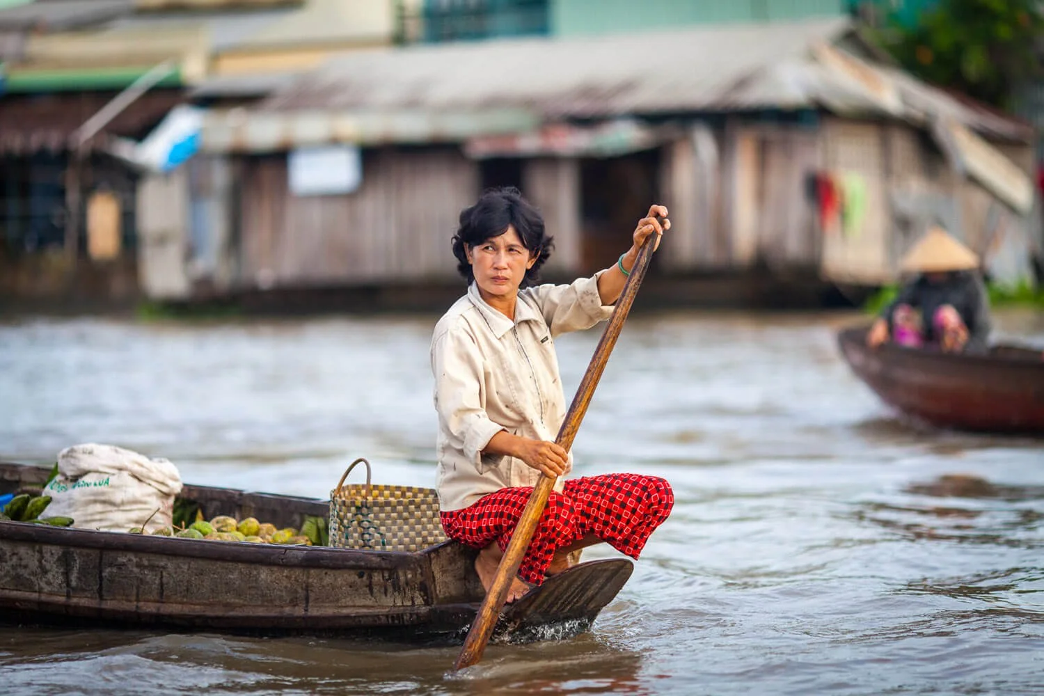 Vietnamese woman paddles her boat at the morning floating market at Phong Điền, Cần Thơ, Vietnam. Ian Taylor Photographer.