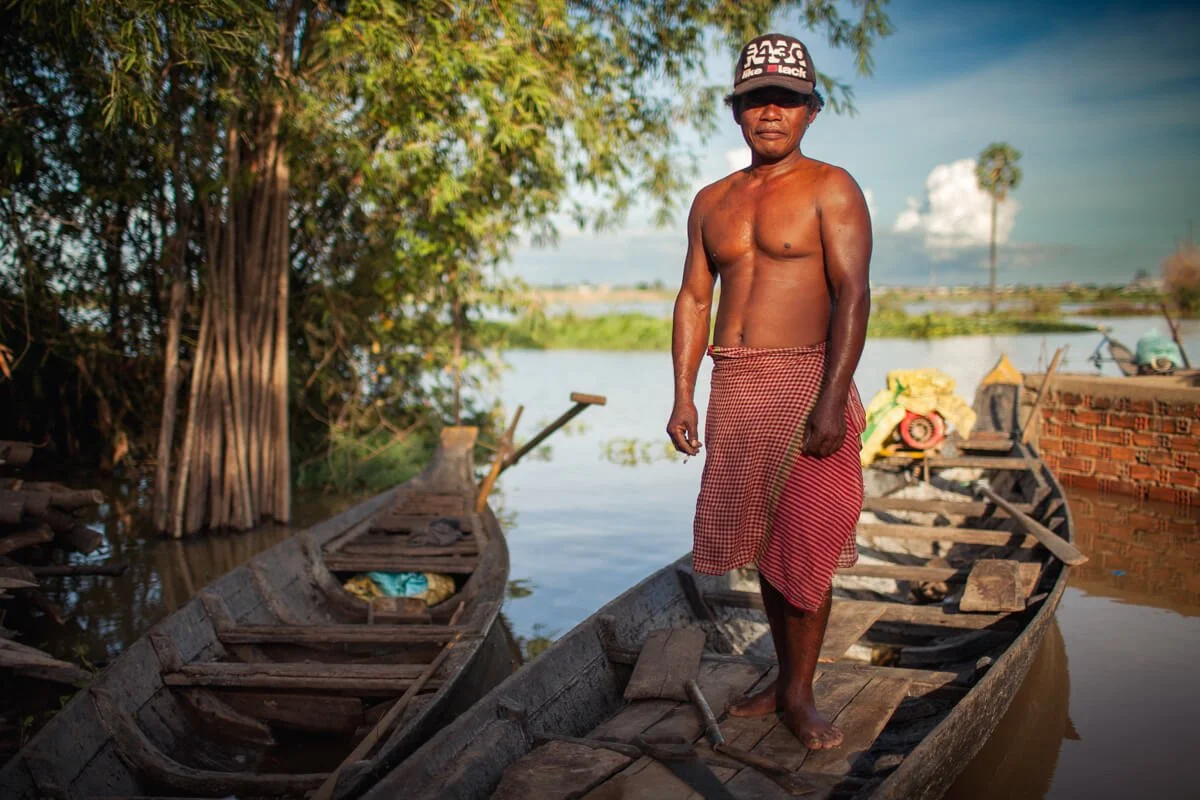 Cambodian man stands in his boat on the Mekong River near Phnom Penh, for CGIAR.