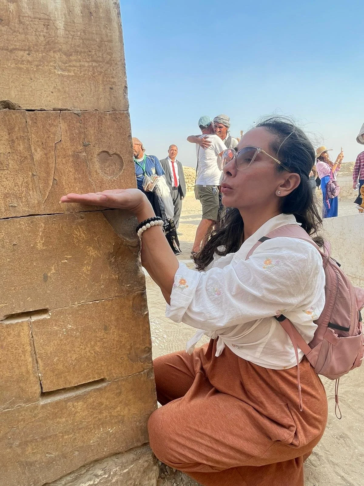 Stephanie kneeling beside an ancient stone heart carving in Egypt