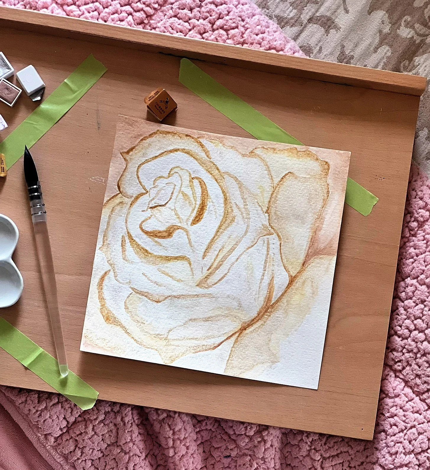 Ivory-and-gold rose artwork in progress on a wooden drawing board.