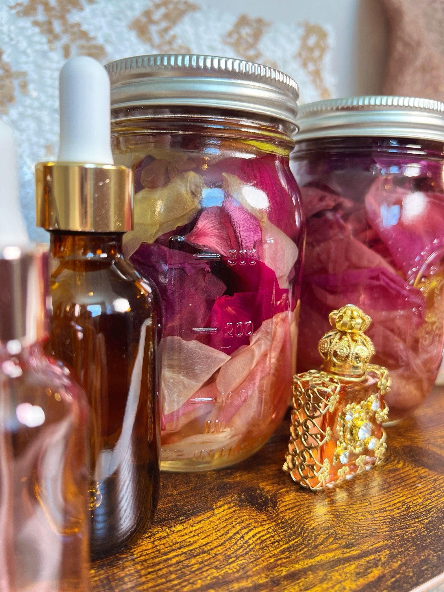 Rose-filled jars, amber and blush bottles, and an ornate gold vessel.
