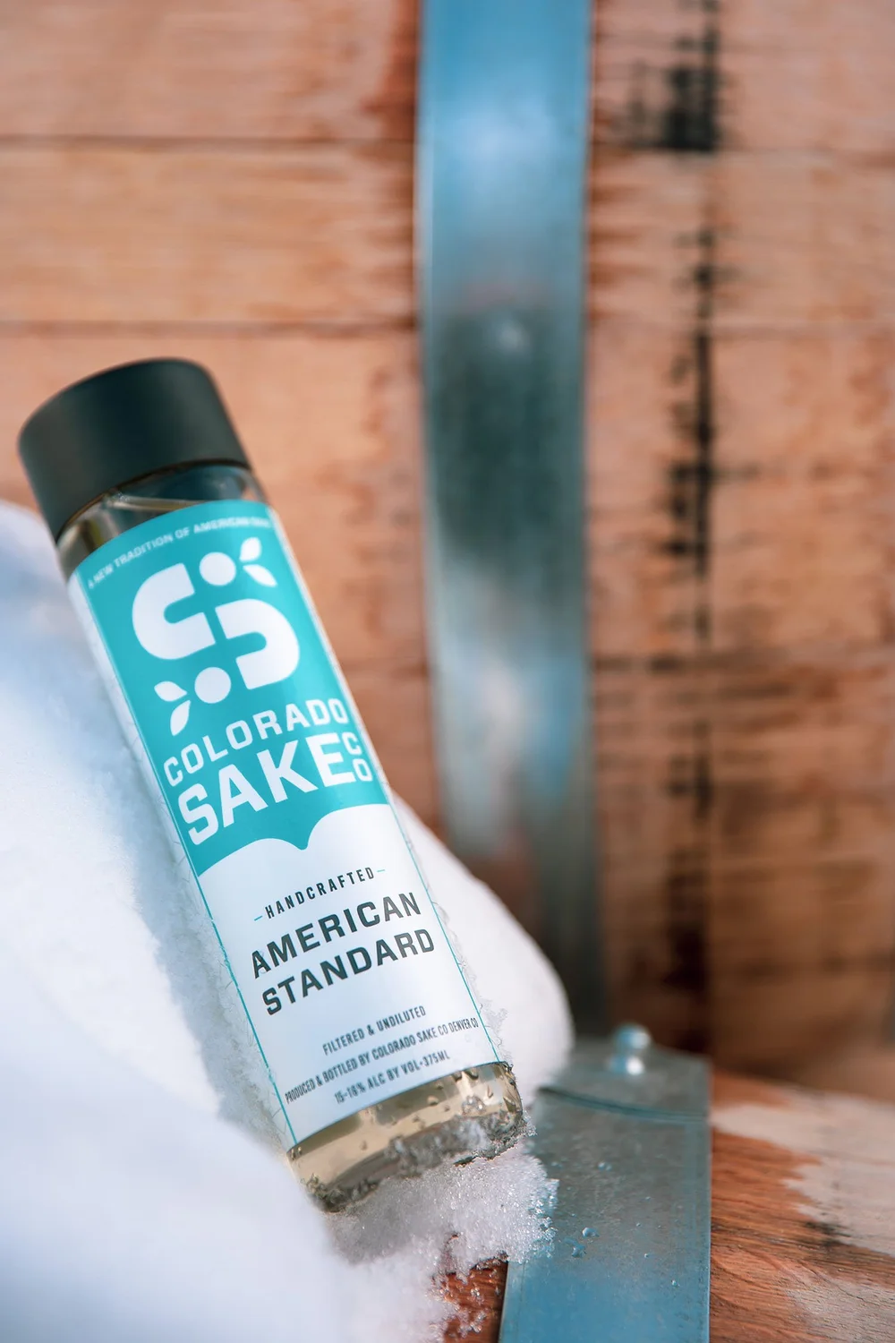 A bottle of Colorado Sake Co. American Standard chilling in snow