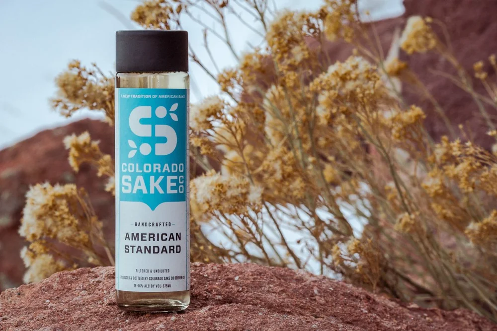 A bottle of Colorado Sake Co. American Standard sake on red Colorado sandstone