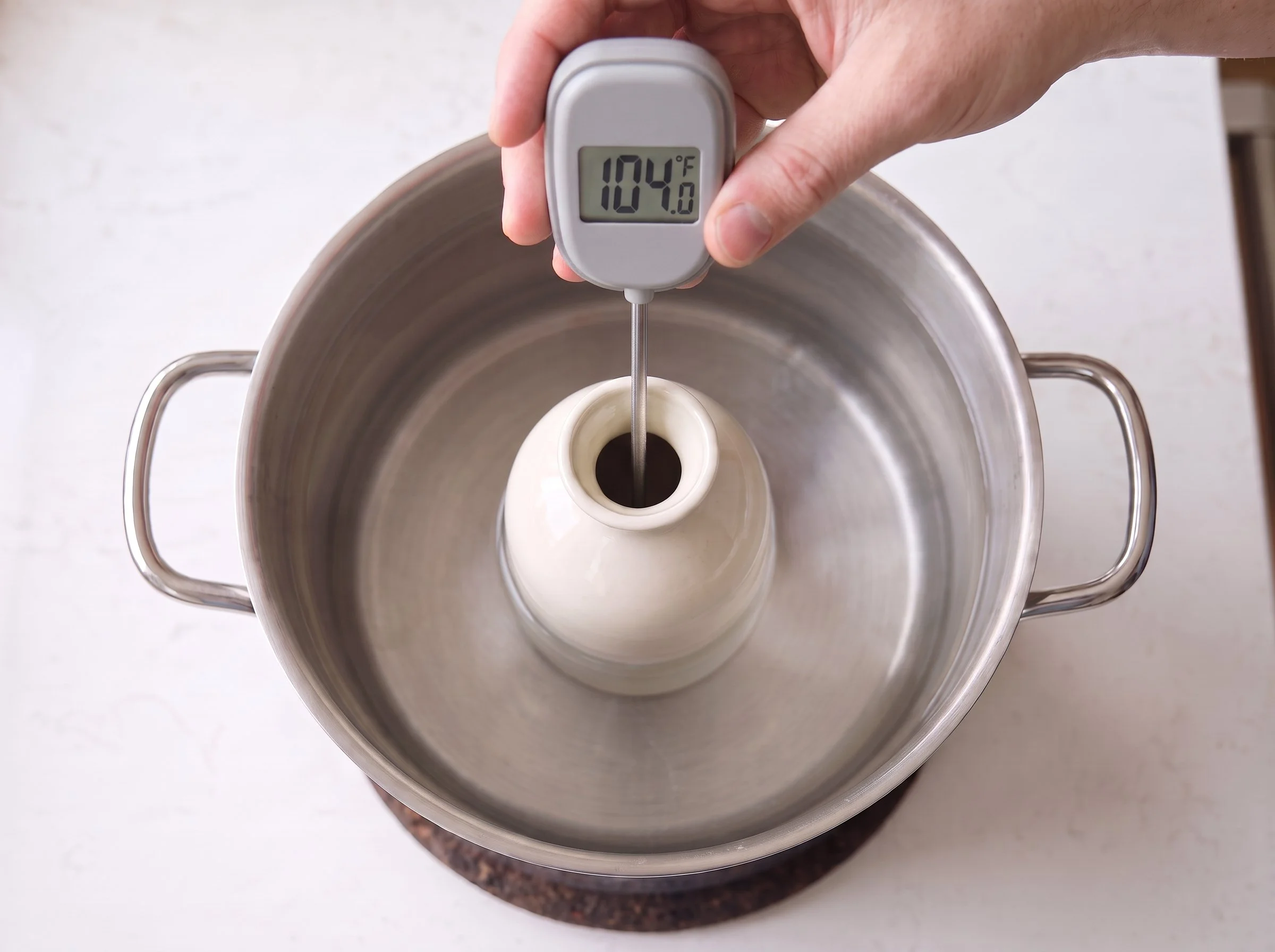 Thermometer probe passing through the open top of a sake carafe, with its display facing the camera.