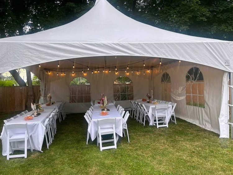 Marquee tent with dressed tables, white chairs and string lights