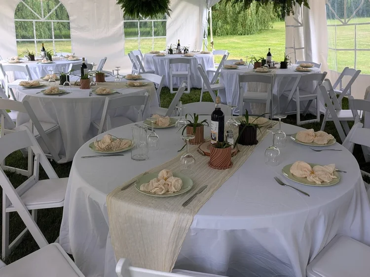 Round tables with white tablecloths and runners in a marquee tent
