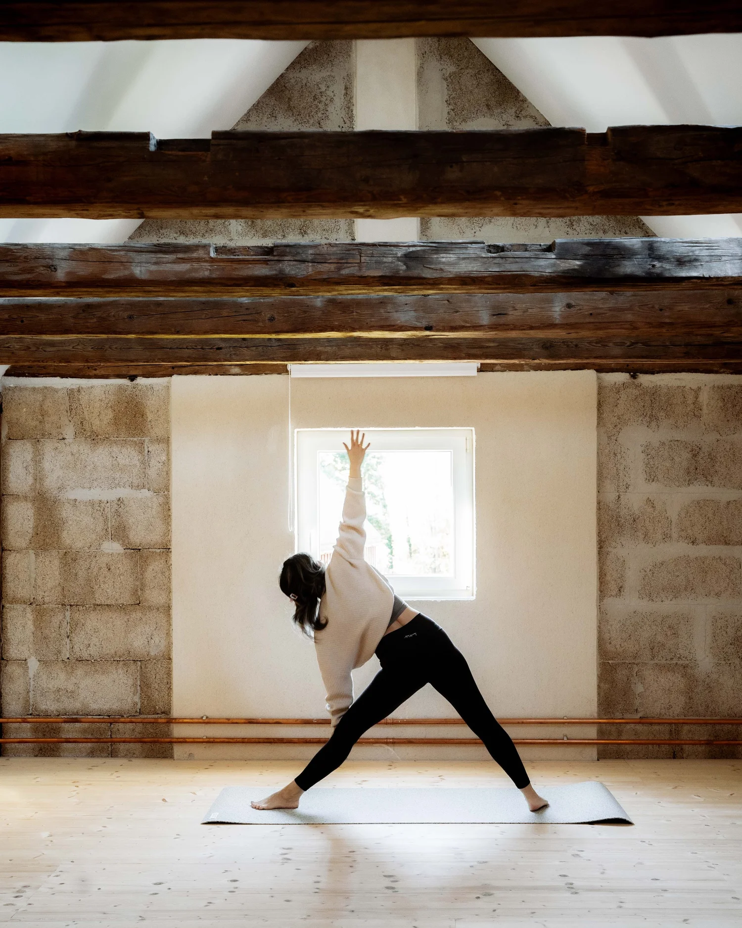 Marella beim Yoga im lichtdurchfluteten Speicher von d’Kammer unter alten Holzbalken