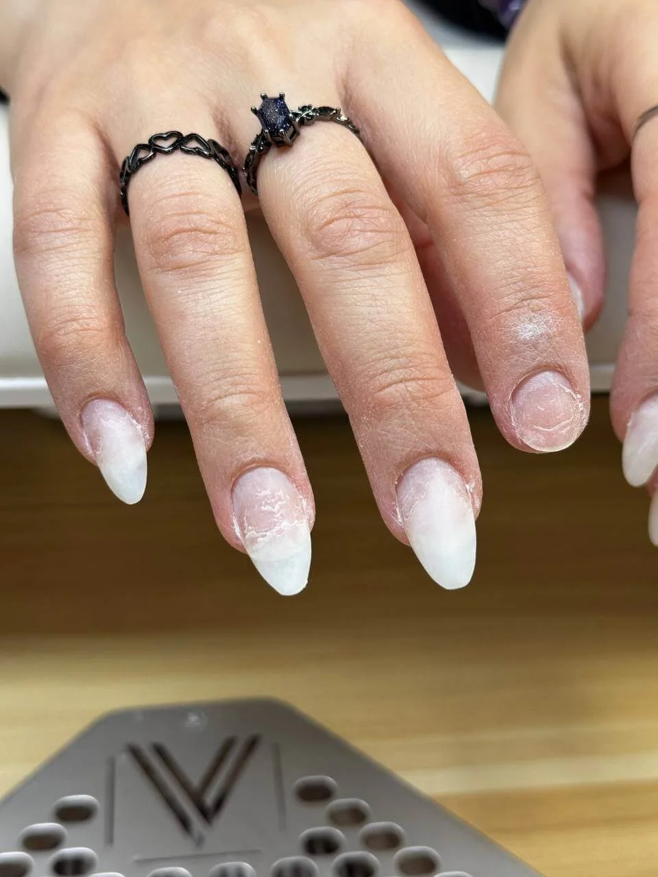 Long light-colored almond nails before shortening and reshaping for a purple cat eye manicure