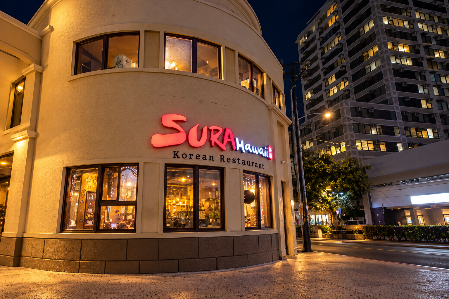 Sura Hawaii's illuminated two-story corner facade, with upper windows and the Honolulu sidewalk visible at night