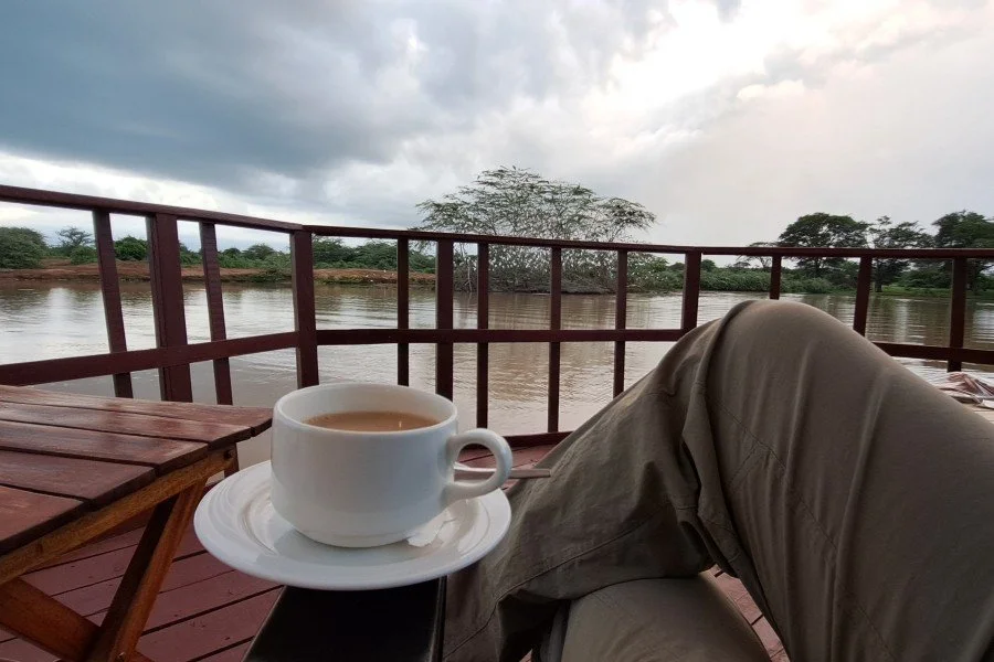 Older traveller calmly sipping tea at the sunset, enjoying me-time over a lake scenery.