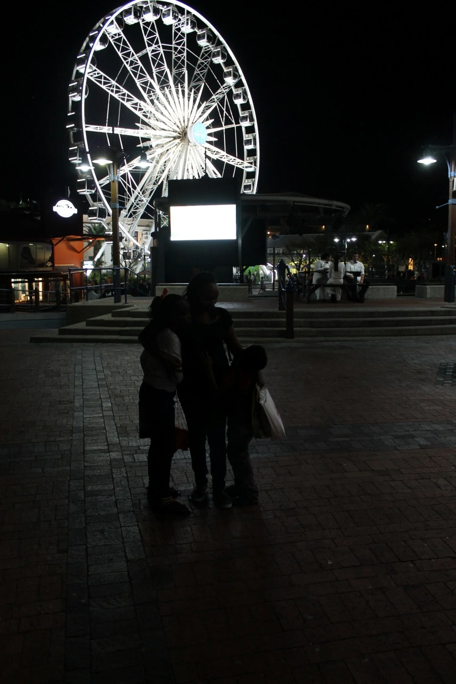 Parent with chronic pain resting calmly near airport gate while kids play nearby